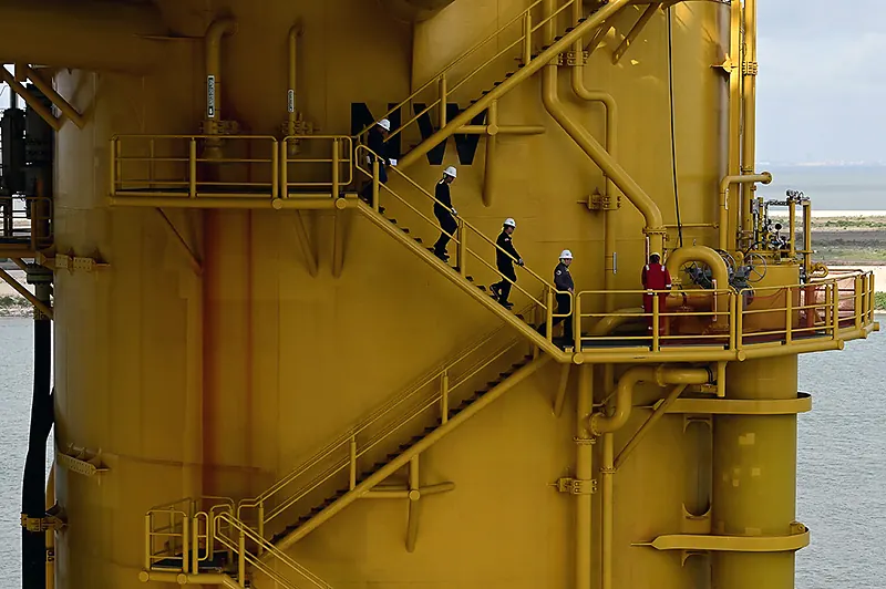 Inspectores recorren las escaleras de una plataforma de producción de hidrocarburos.