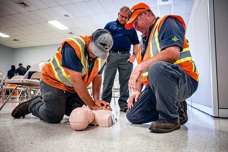 Trabajadores practican reanimación cardiopulmonar con un maniquí durante una capacitación en primeros auxilios.